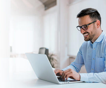 Foto de homem em frente a um notebook sorrindo